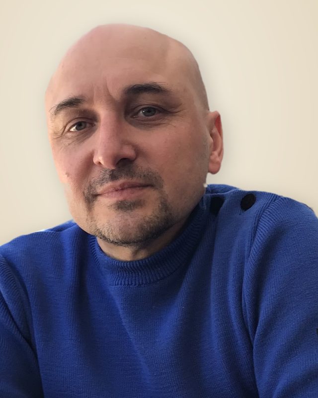 Portrait d'Etienne Buraud, souriant, en pull bleu